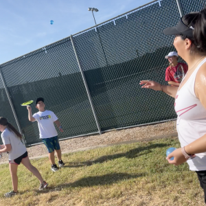 Coach Morgan tossing a water balloon to a junior.- Summer 2023